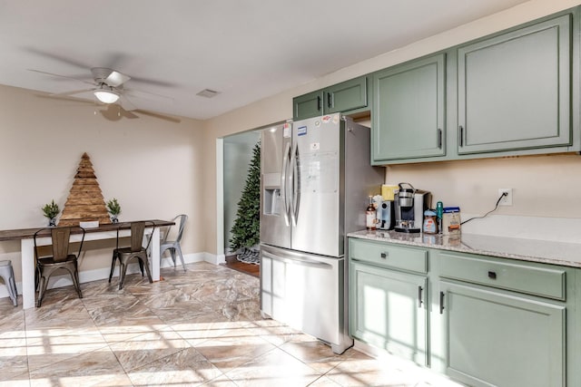 kitchen featuring green cabinets, ceiling fan, light stone counters, and stainless steel refrigerator with ice dispenser