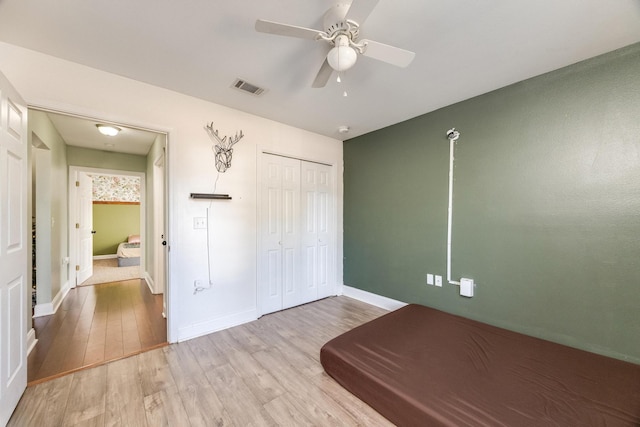 unfurnished bedroom featuring ceiling fan, a closet, and light hardwood / wood-style floors