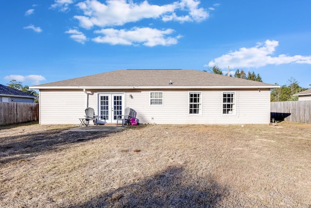 back of property with french doors and a lawn