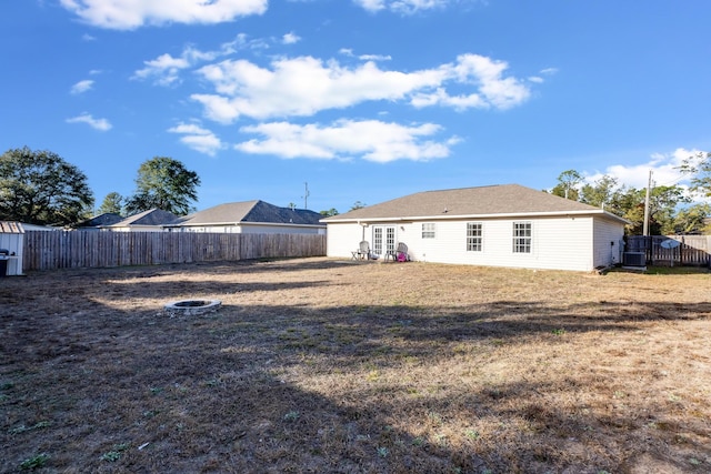 rear view of property with central AC unit and a yard