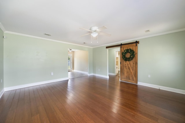 empty room with hardwood / wood-style flooring, a barn door, baseboards, visible vents, and ceiling fan