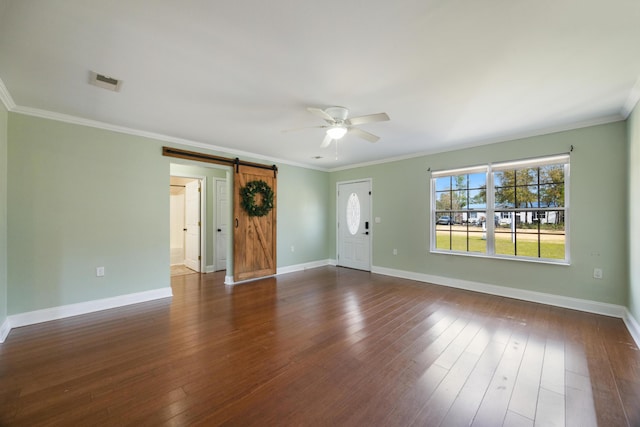 spare room featuring dark wood-type flooring, a barn door, ceiling fan, and visible vents