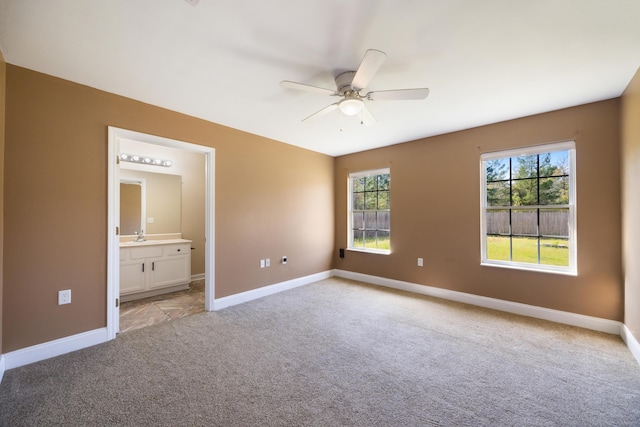 unfurnished bedroom featuring a sink, connected bathroom, baseboards, and light colored carpet