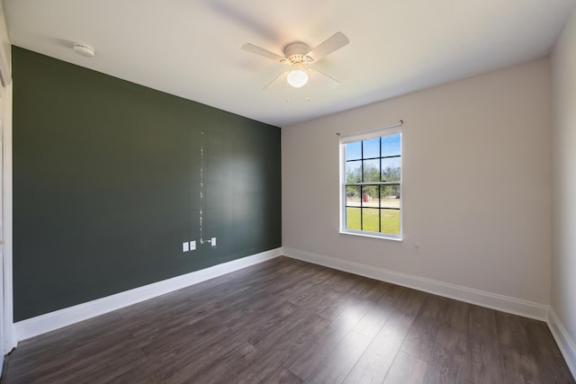 spare room featuring dark wood-type flooring, baseboards, and a ceiling fan
