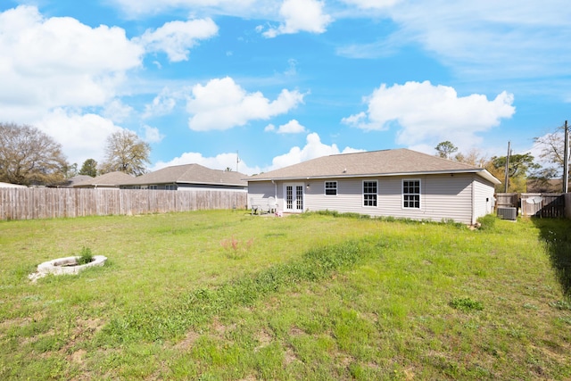 rear view of property with a lawn, a fenced backyard, french doors, and cooling unit
