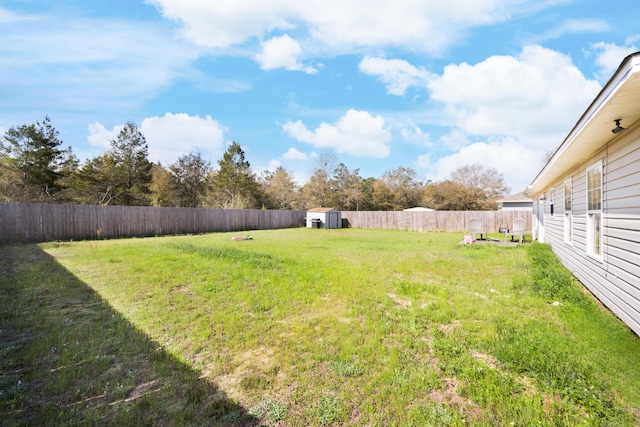 view of yard with a storage unit, a fenced backyard, and an outdoor structure