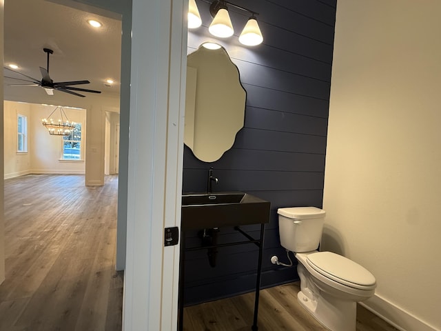 bathroom featuring ceiling fan with notable chandelier, baseboards, toilet, and wood finished floors