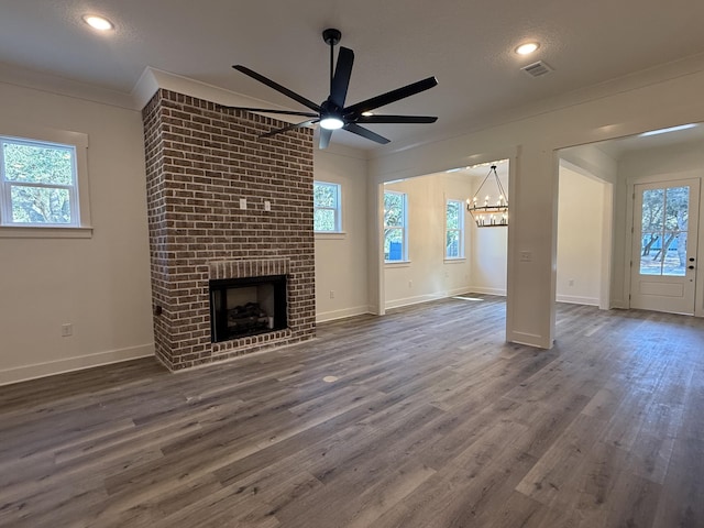 unfurnished living room featuring a brick fireplace, baseboards, ornamental molding, and wood finished floors