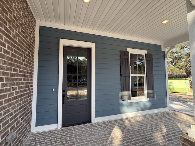 property entrance with brick siding and a porch