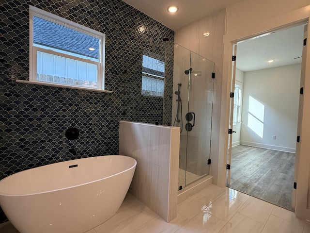 full bath featuring a stall shower, a freestanding bath, tile walls, and recessed lighting