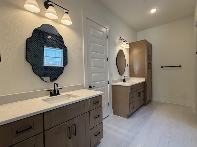 bathroom with baseboards, two vanities, and a sink