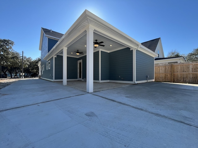 view of side of property with fence, a patio, and ceiling fan