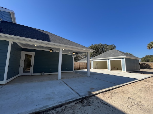 exterior space featuring ceiling fan, an outbuilding, fence, and a garage