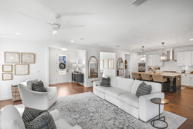 living room featuring dark hardwood / wood-style flooring, ceiling fan, ornamental molding, and sink