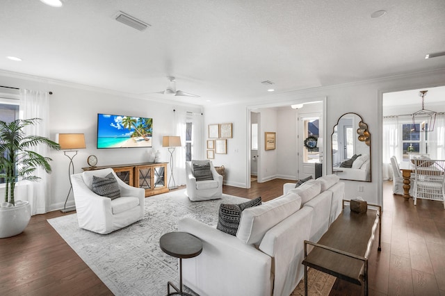 living room featuring ceiling fan with notable chandelier, dark wood-type flooring, and ornamental molding