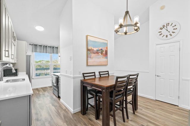 dining space featuring sink, light wood-type flooring, and a notable chandelier