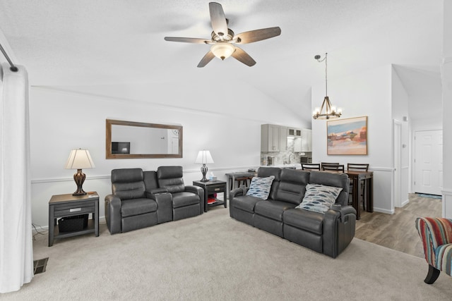 living room featuring ceiling fan with notable chandelier, light colored carpet, and lofted ceiling