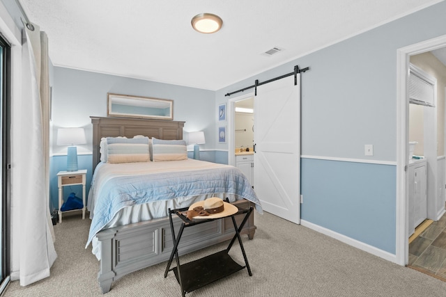 carpeted bedroom with washing machine and clothes dryer, connected bathroom, and a barn door