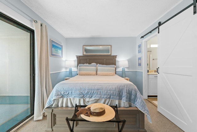 bedroom featuring a barn door, light colored carpet, and ensuite bath