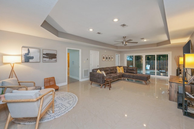 living room featuring a raised ceiling and ceiling fan