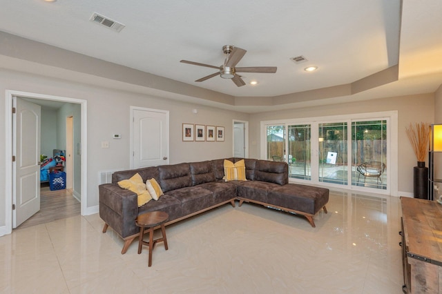 living room featuring a raised ceiling and ceiling fan