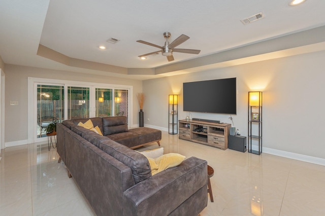 living room with ceiling fan and a tray ceiling