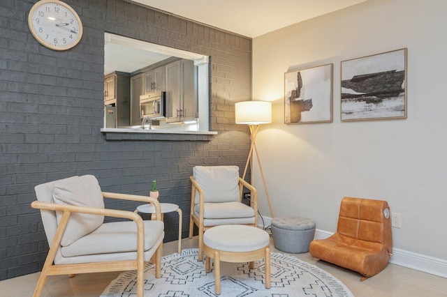 living area with brick wall and light tile patterned floors