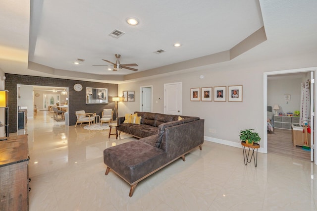 living room with ceiling fan and a tray ceiling