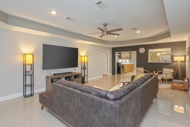 living room with a raised ceiling and ceiling fan