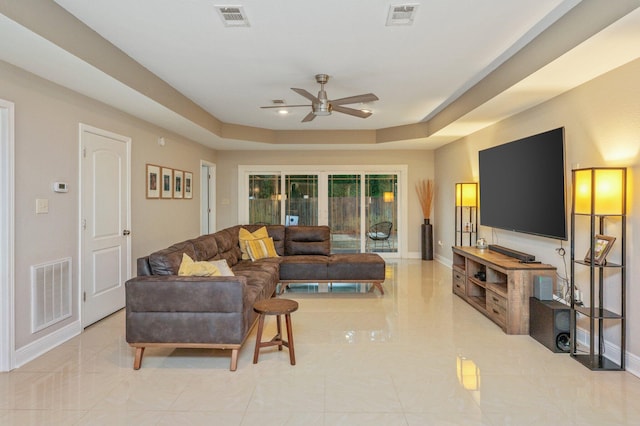 living room with ceiling fan and a tray ceiling