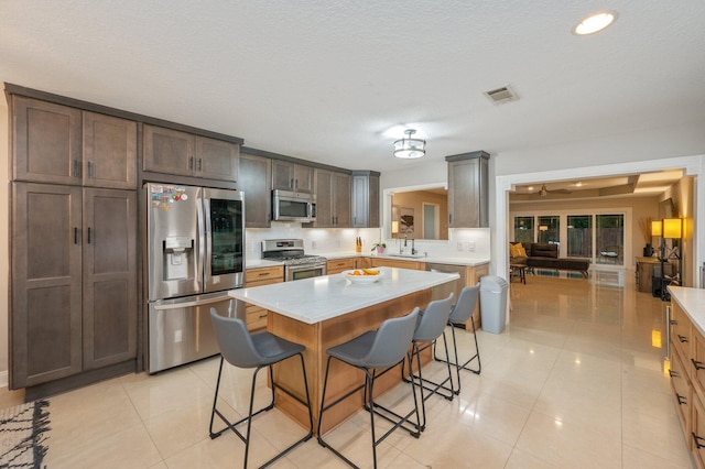 kitchen with appliances with stainless steel finishes, a center island, a breakfast bar area, and light tile patterned floors