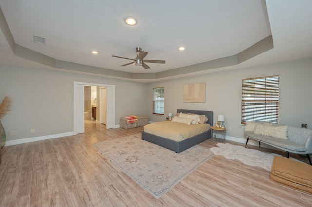 bedroom featuring a raised ceiling, ceiling fan, and light hardwood / wood-style flooring