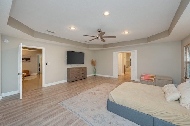 bedroom featuring a raised ceiling, ceiling fan, and light hardwood / wood-style flooring