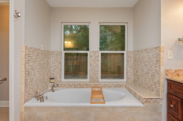 bathroom featuring tiled tub and vanity