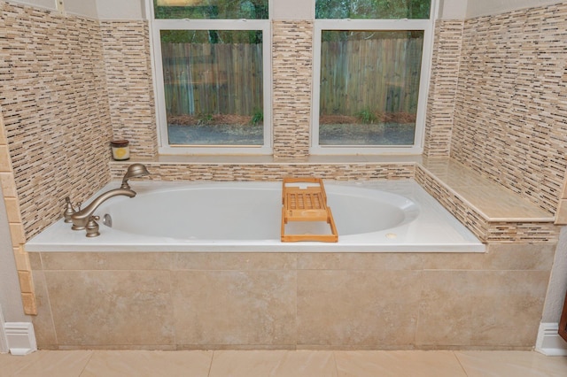 bathroom featuring a relaxing tiled tub and tile patterned flooring