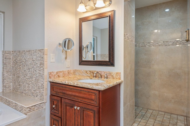 bathroom with a tile shower and vanity