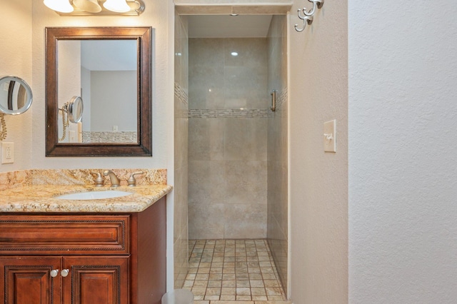 bathroom with tiled shower and vanity