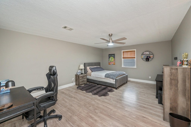 bedroom with a textured ceiling, ceiling fan, and light hardwood / wood-style flooring