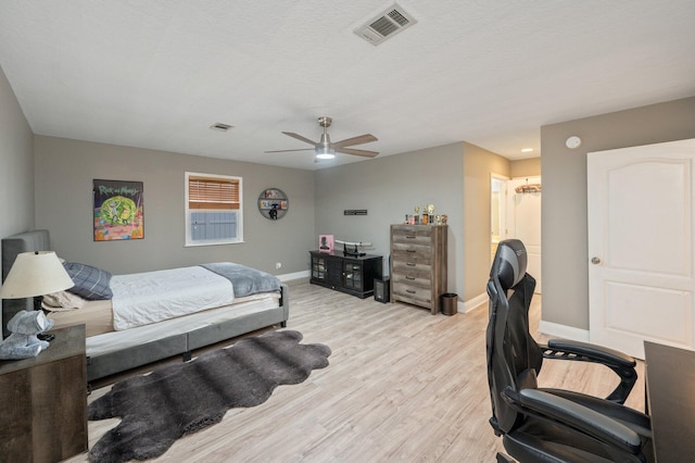 bedroom with a textured ceiling, ceiling fan, and light wood-type flooring