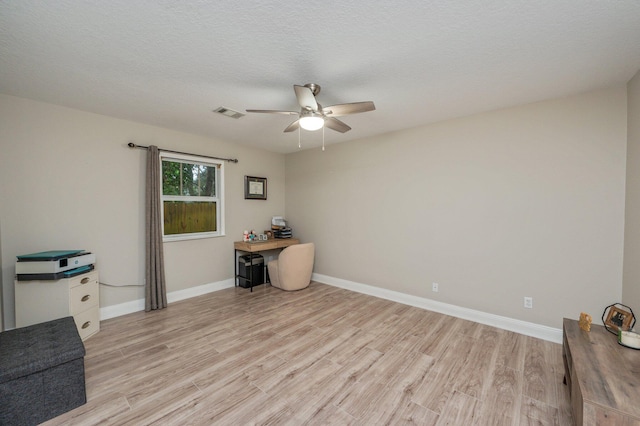 interior space with a textured ceiling, ceiling fan, and light hardwood / wood-style floors