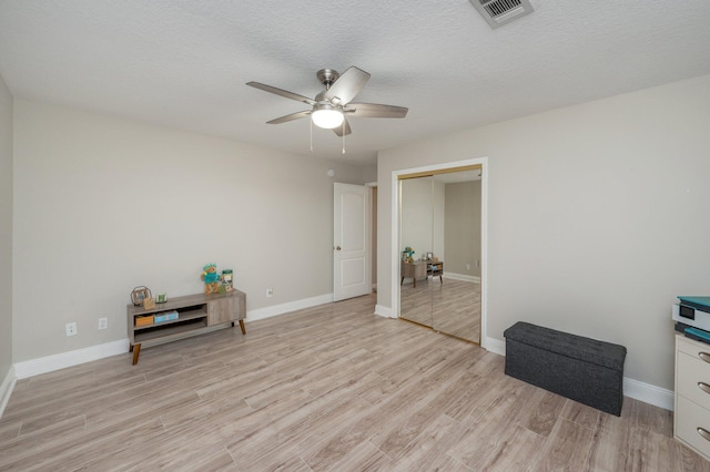 spare room with a textured ceiling, light wood-type flooring, and ceiling fan