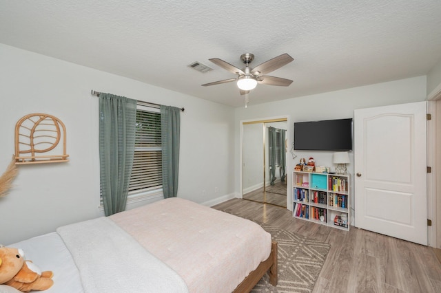 bedroom with hardwood / wood-style flooring, a textured ceiling, ceiling fan, and a closet