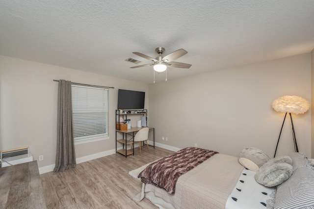 bedroom with ceiling fan, light hardwood / wood-style flooring, and a textured ceiling