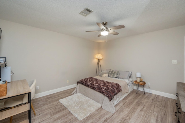 bedroom featuring ceiling fan, light hardwood / wood-style flooring, and a textured ceiling