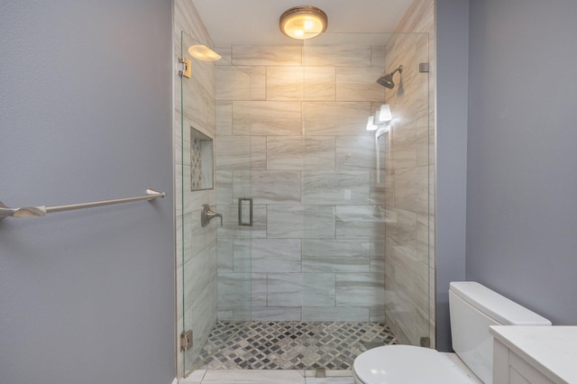 bathroom featuring toilet, a shower with shower door, and vanity