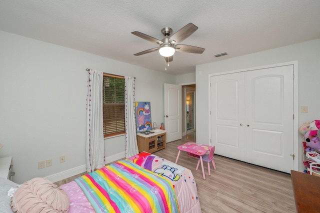 bedroom featuring ceiling fan, light wood-type flooring, a closet, and a textured ceiling