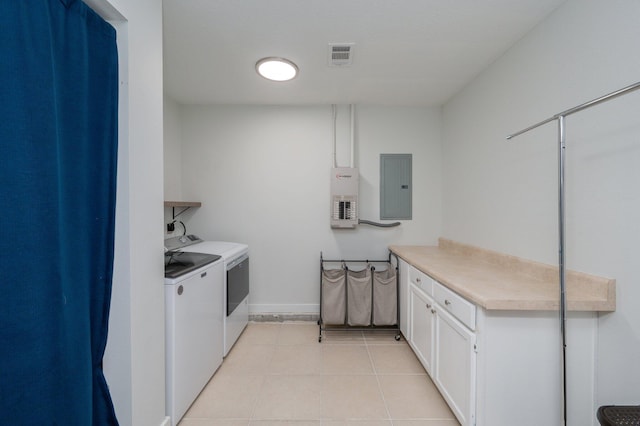 laundry room featuring electric panel, cabinets, washer and dryer, and light tile patterned floors