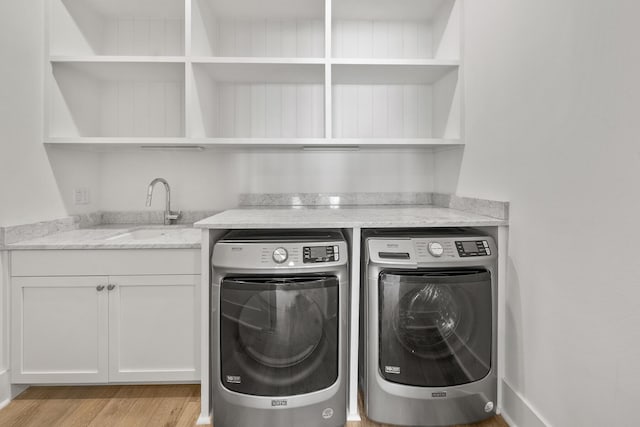 washroom with sink, washer and dryer, and light wood-type flooring