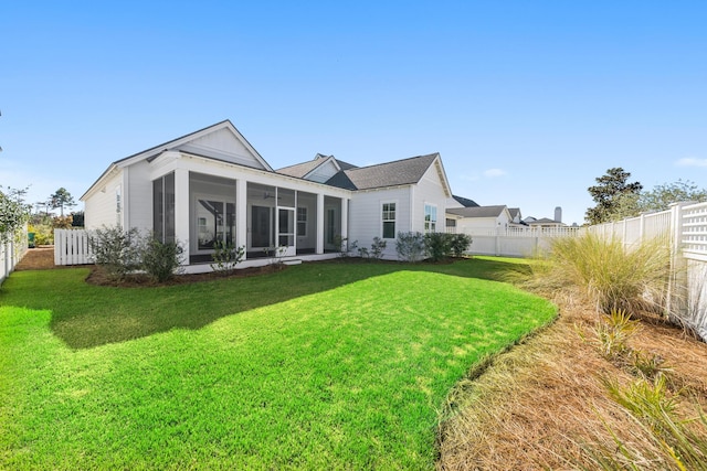 rear view of house featuring a sunroom and a lawn