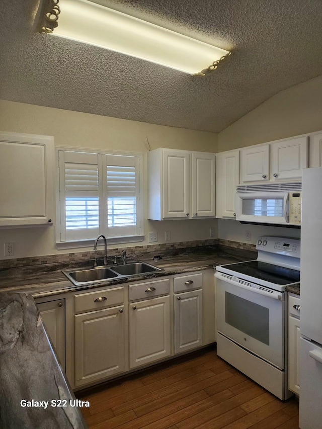 kitchen featuring sink, dark hardwood / wood-style floors, lofted ceiling, white appliances, and white cabinets